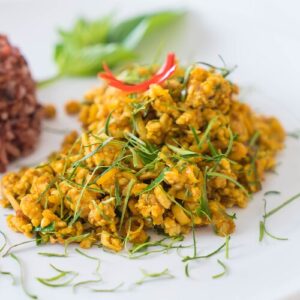 Porc sauté à la pâte de curry jaune, présenté dans une assiette blanche